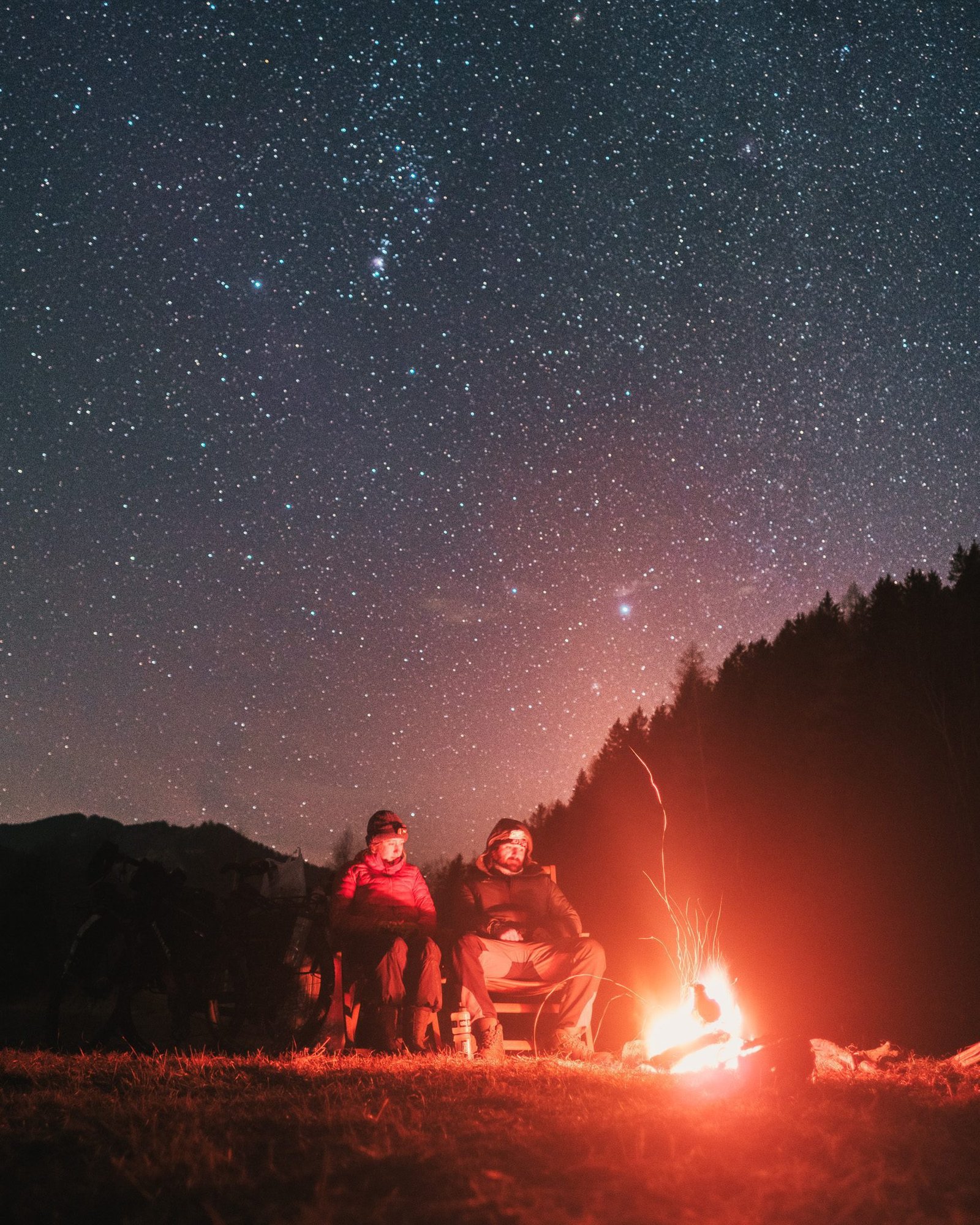 Astro photo of couple camping beneath stars with a fire